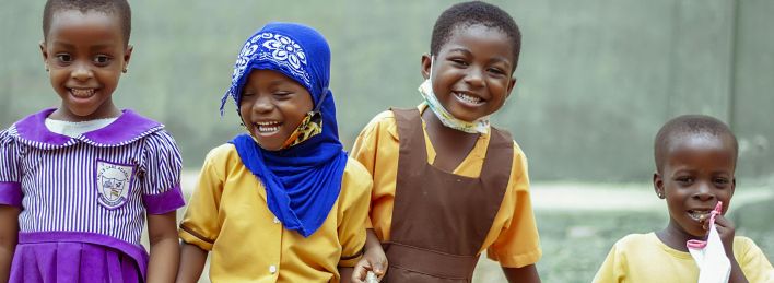 Happy children in school uniforms smiling and enjoying break time outside in Accra, Ghana.